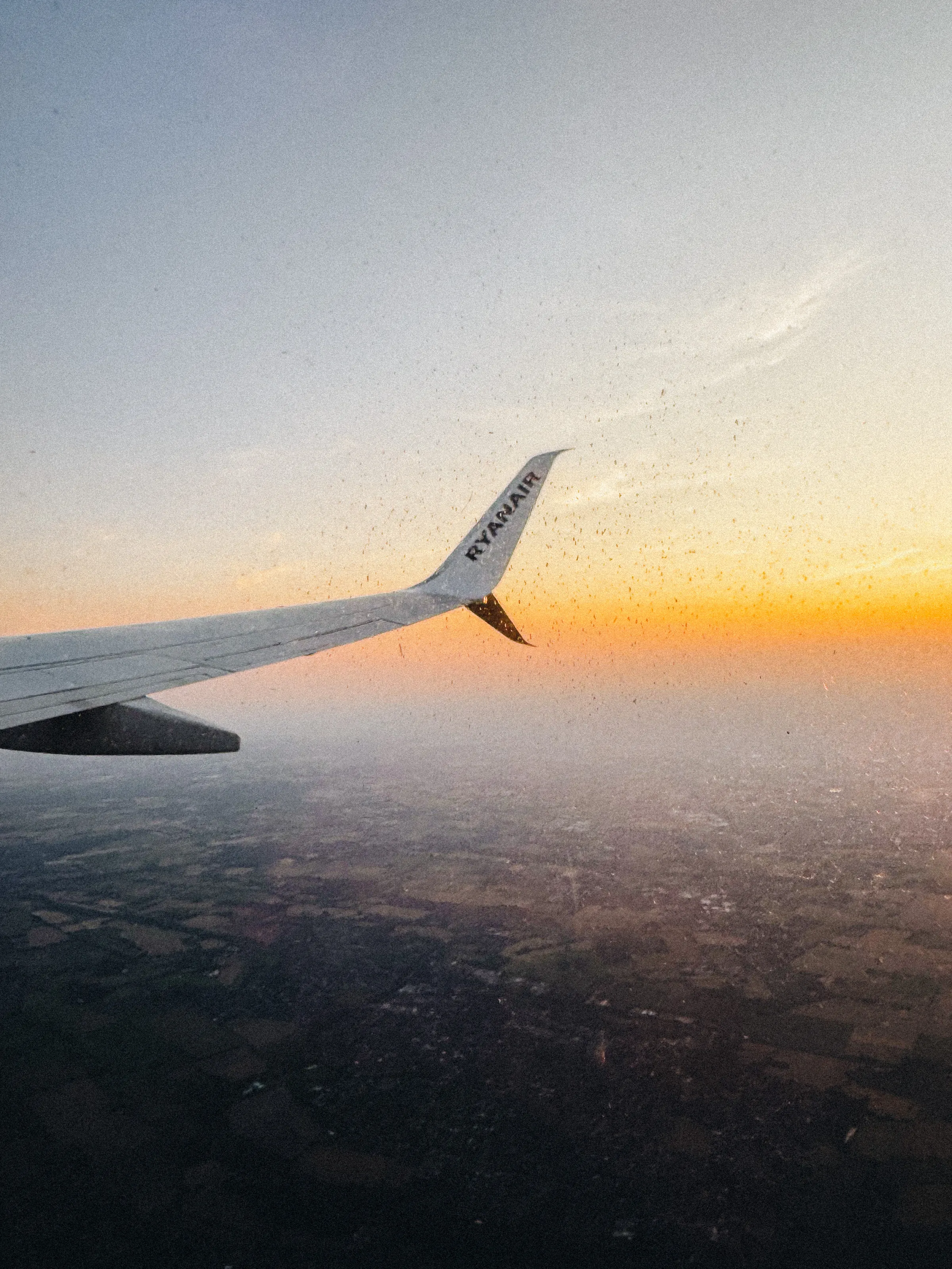 The view from an airplane window: a wing catching the light of a sunset sky