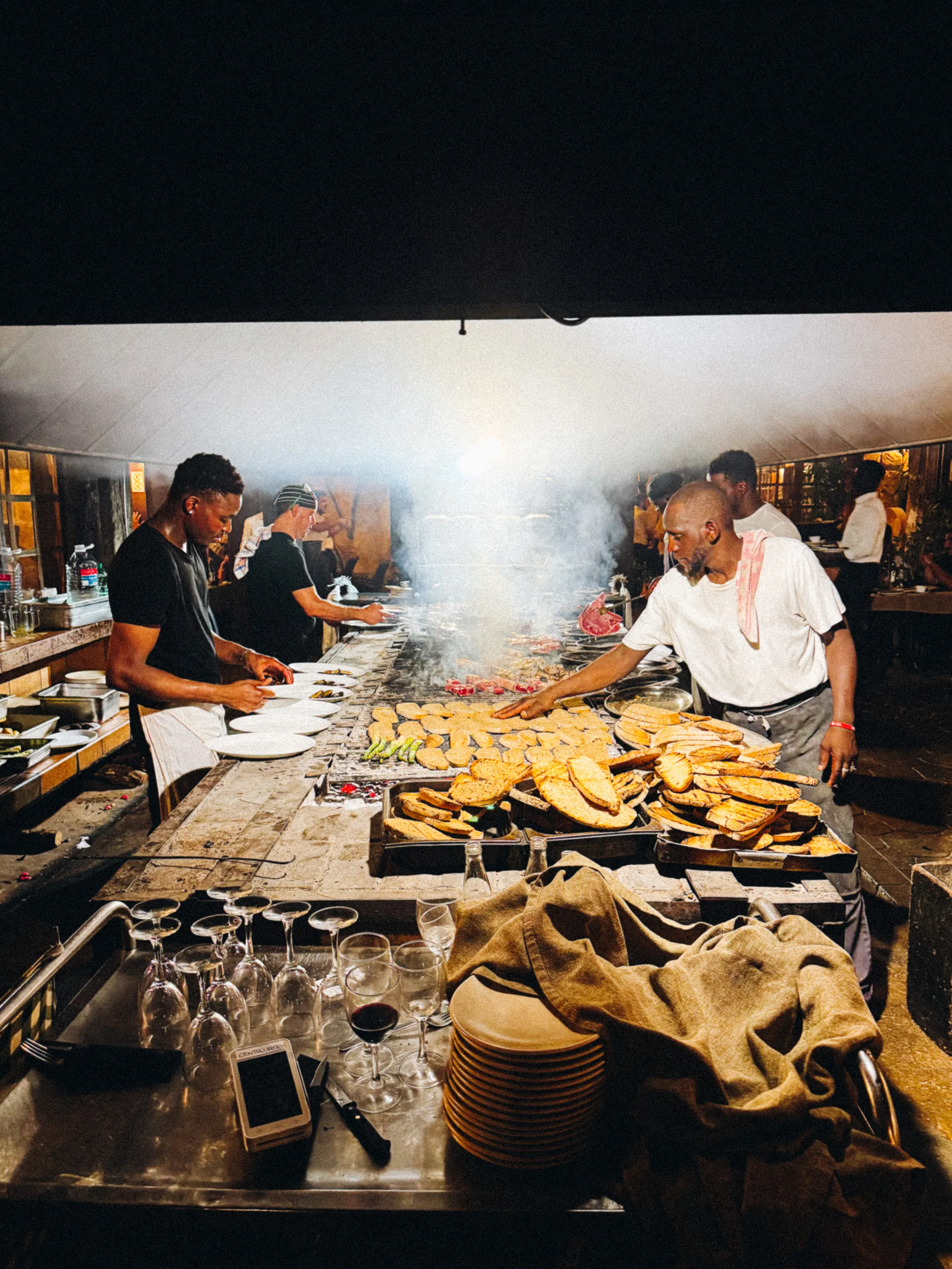 A restaurant kitchen with cooks working over a hot grill