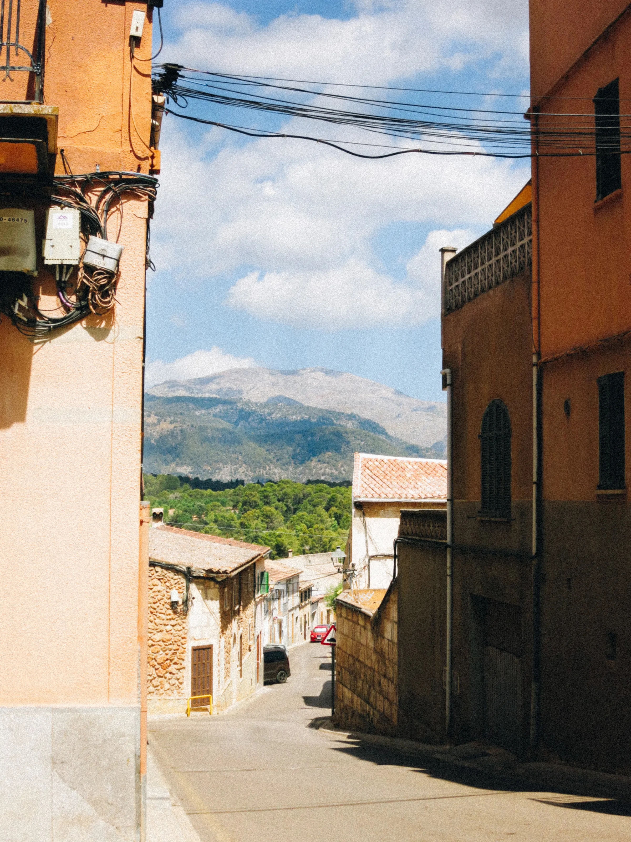 A narrow street between orange buildings, mountains visible at the far end